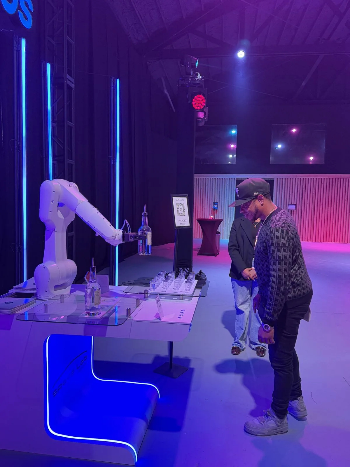 The RoboBar robotic bartender pouring drinks under kinetic lighting at a live event