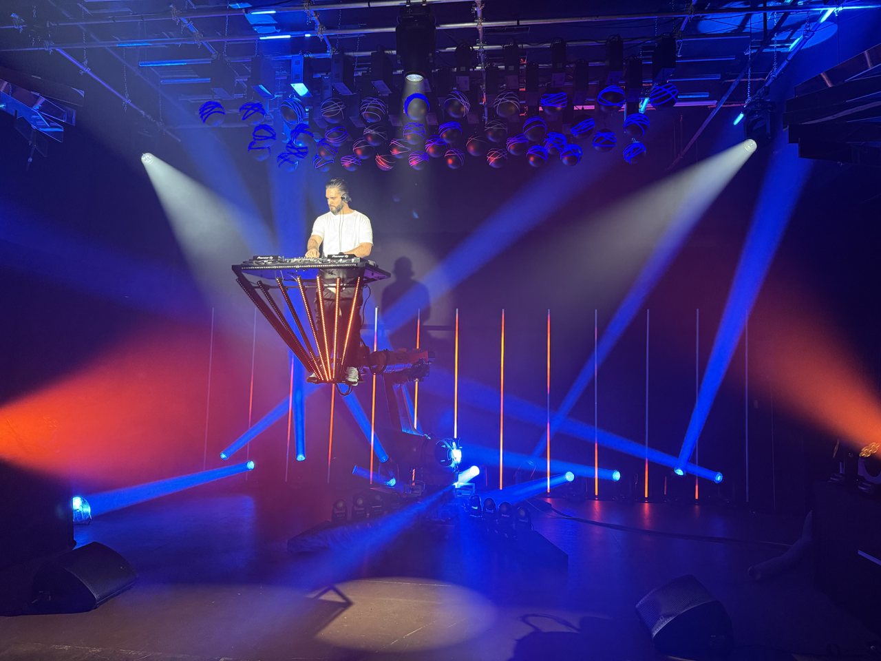 Robotic DJ booth lifted by a KUKA robotic arm with blue and red beams